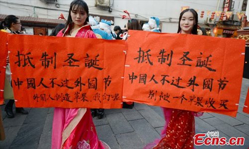 College students wearing traditional Chinese clothing join a campaign to boycott Christmas celebrations on a street in Changsha, Central China��s Hunan province on December 24, 2014. With slogans saying ��Boycott Christmas-Chinese don��t celebrate foreign festivals�� in hands, these students call on people to focus on Chinese traditional festivals and celebrate festivals in a rational way. (Source: China News Service/ Yang Huafeng)