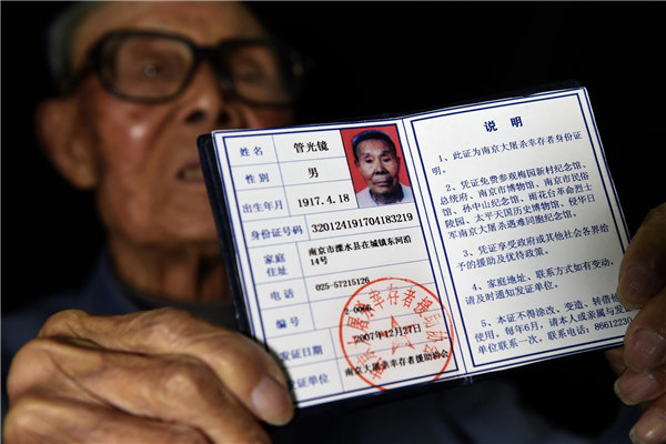 Guan is pictured showing his survivor identification and posing with his daughters. His oral testimony about his survival was published in a book last year. (Xinhua)