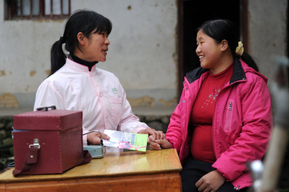 A family planning officer explains a healthcare pamphlet to a pregnant woman in Zhengang, Jiangxi. ��Photo/Xinhua��