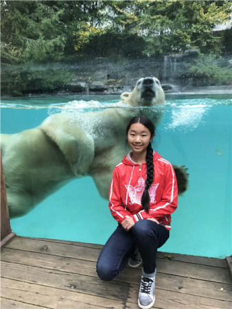 Chinese girl Zhang Jiahe poses with a polar bear while visiting a zoo in France. ��Photo by Herve Fabre/Provided to China Daily��