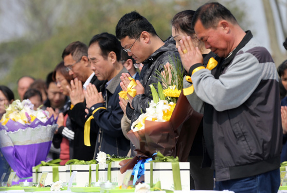 People pray in the cemetery before burying ashes under saplings on Saturday. ��Photo: China Daily /Wang Zhuangfei)