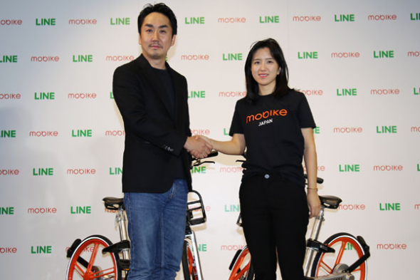 Hu Weiwei, founder and president of Mobike, right, joined hands with Takeshi Idezawa, president and CEO of LINE, at a ceremony in Japan.��Photo provided to chinadaily.com.cn��